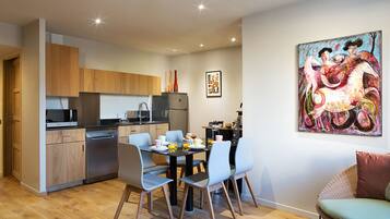 Une cuisine moderne avec des meubles en bois, une table à manger avec des chaises et un tableau accroché au mur.
