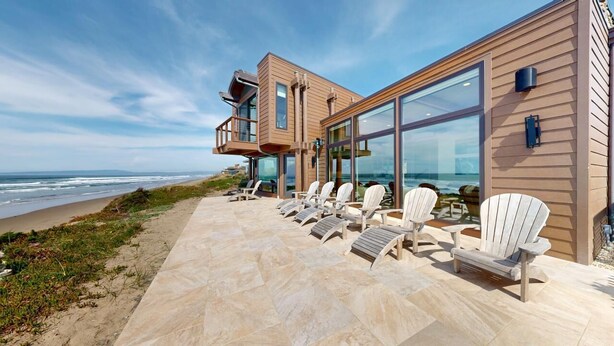 Un edificio frente al mar con terraza y sillones de descanso.