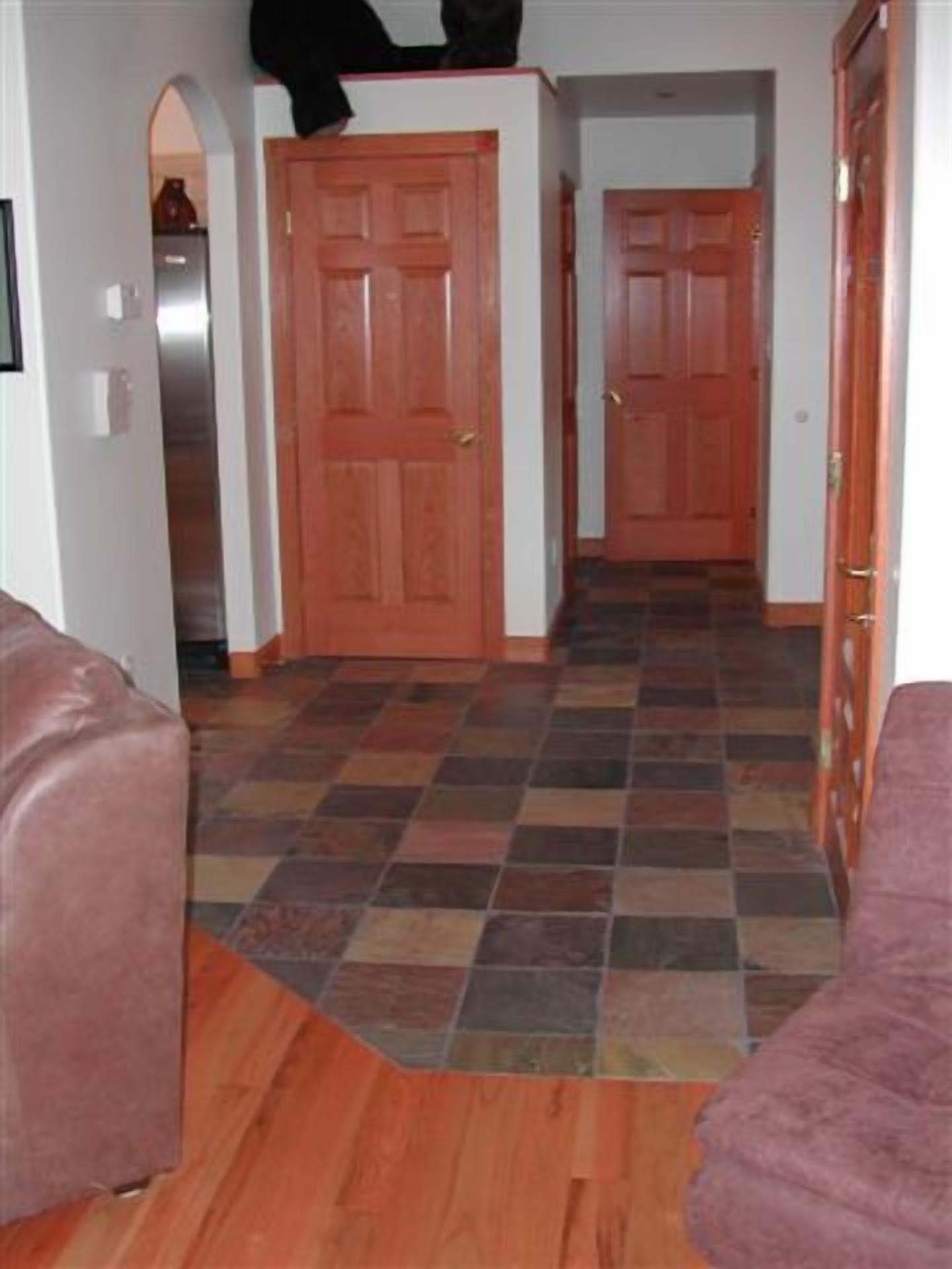 Un couloir avec un plancher en bois et deux portes.