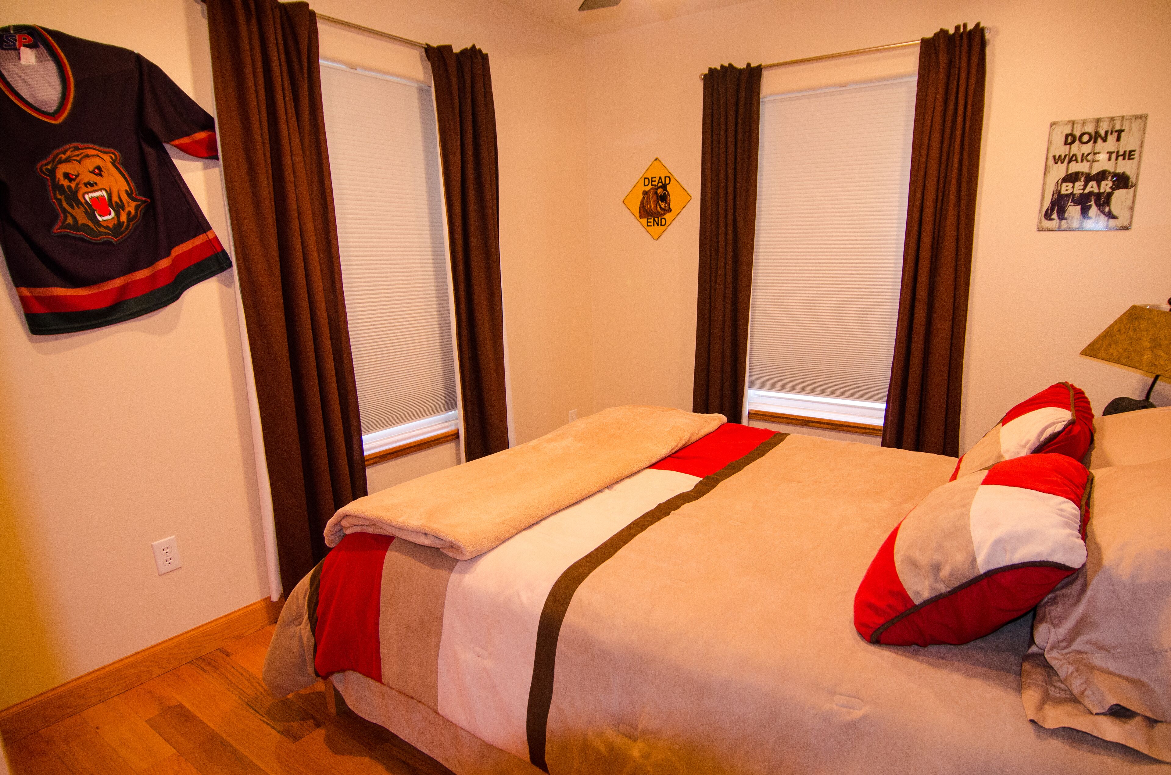 Una habitación de hotel con dos camas, una camiseta de hockey en la pared y un letrero que dice 'No despertar al oso'.