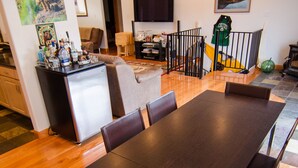A dining area with a long table, chairs, a refrigerator, and a TV mounted on the wall. - Kodiak, Alaska Executive Home  (Kodiak)