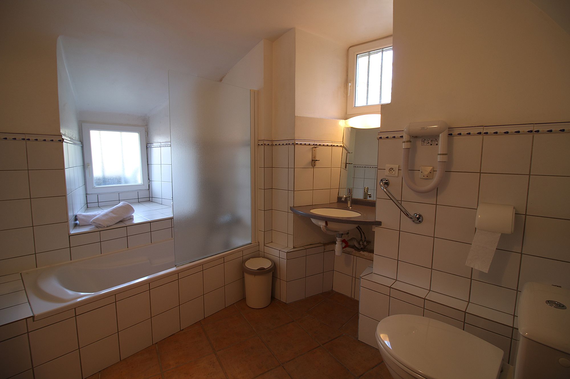 Een badkamer met een bad, toilet, wastafel en raam.
