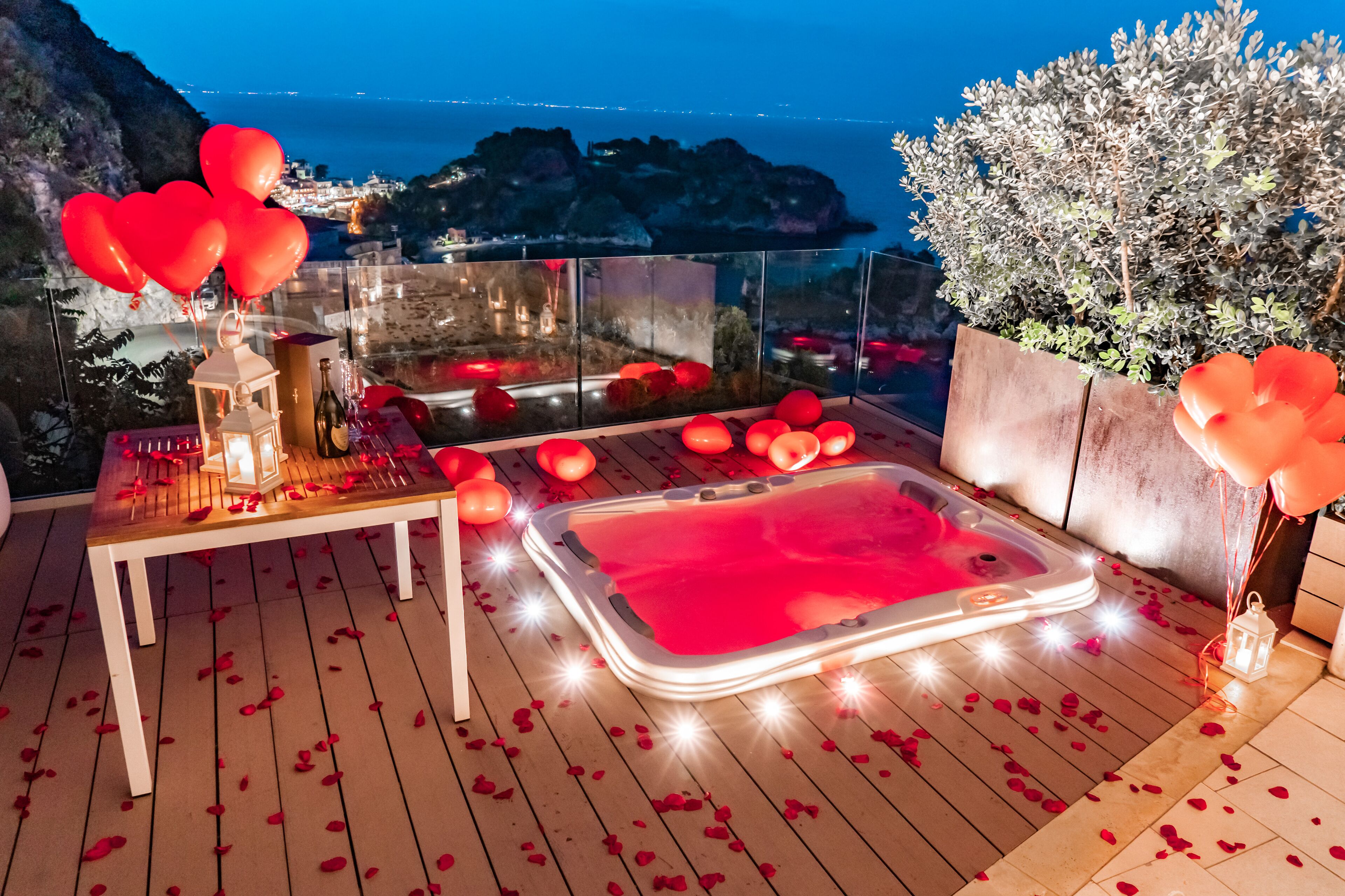 A rooftop terrace with a hot tub, a table with a lantern, and red balloons.
