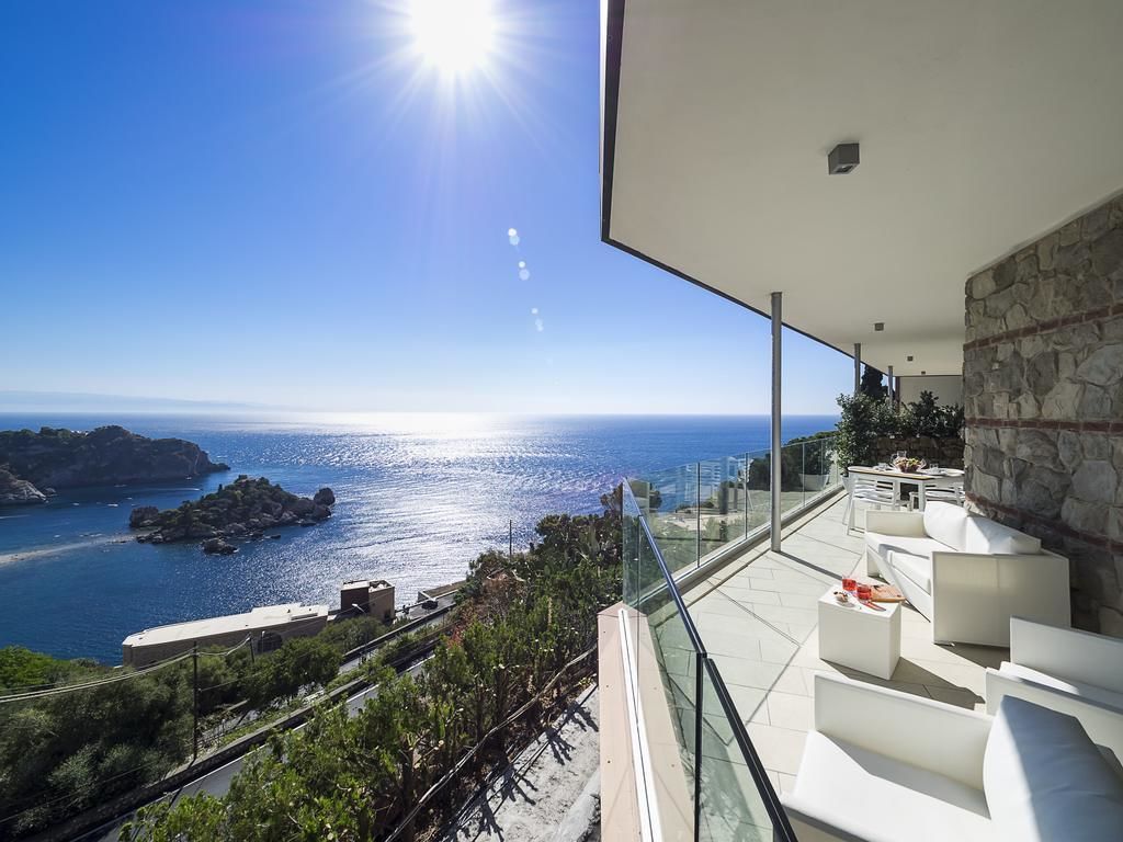 A modern balcony with a clear view of the sea and rocky coastline.