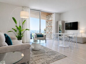 A modern living room with a sofa, coffee table, and dining area with chairs. - Isola Bella Infinity Suites (Taormina)