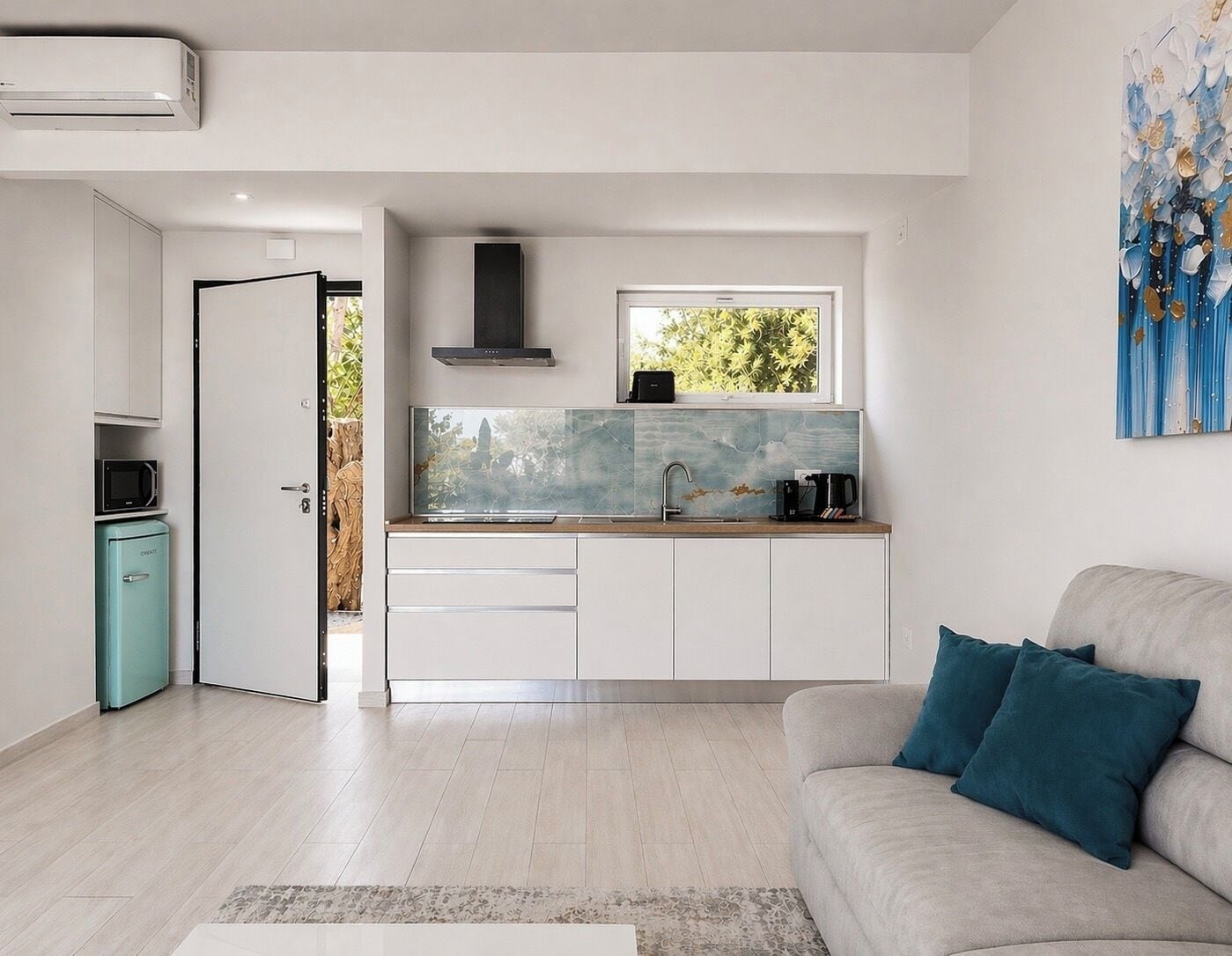 A modern kitchen with a window, white cabinets, and a built-in microwave.