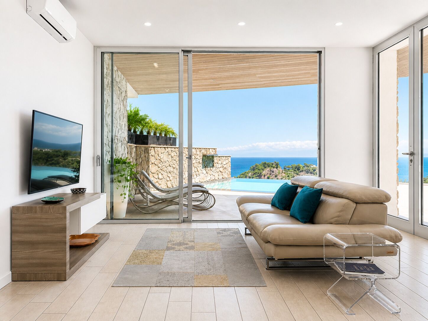 A modern living room with a TV, sofa, and clear glass doors leading to a pool and ocean view.