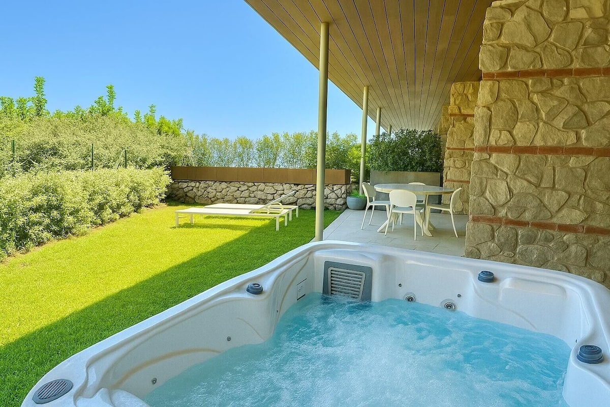 Un jacuzzi con una pared de piedra y una pérgola de madera.