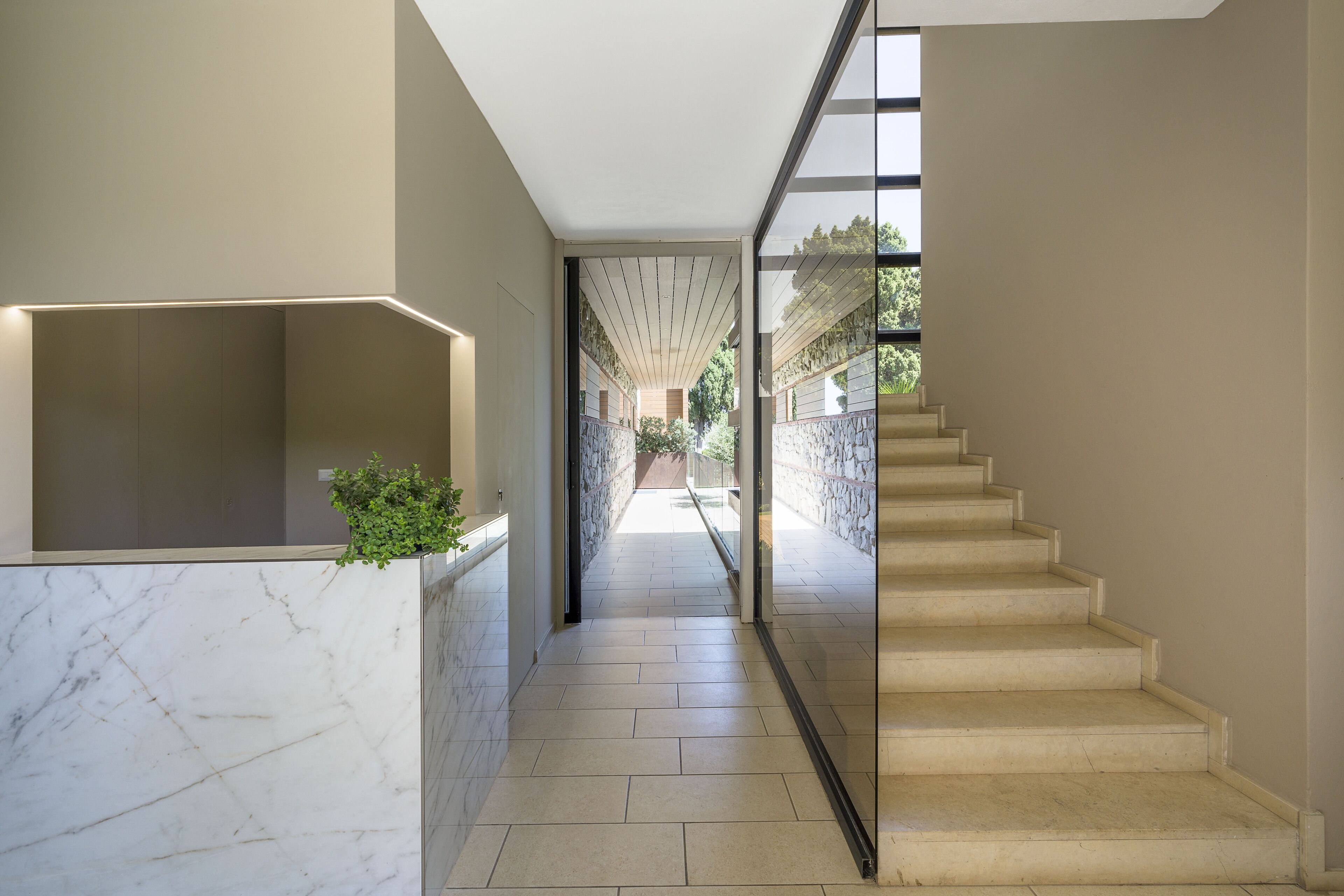 A modern interior with a marble wall, a glass door leading to a balcony, and a staircase.