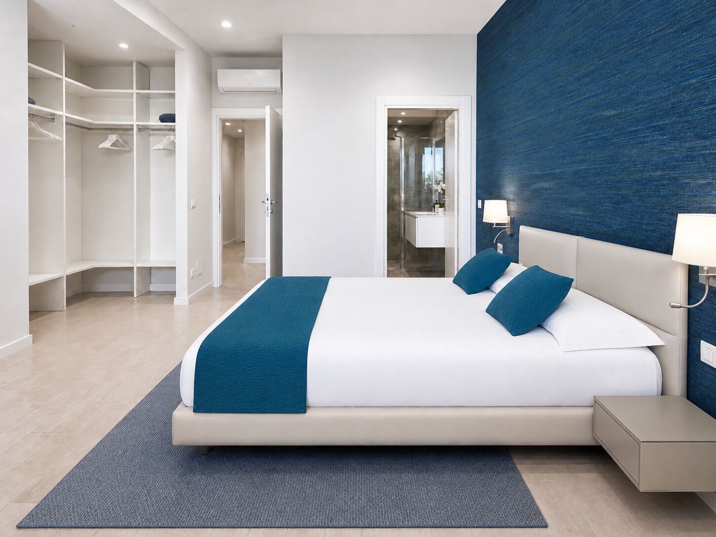 A modern bedroom with a large bed, a walk-in closet, and a bathroom visible through an open door.