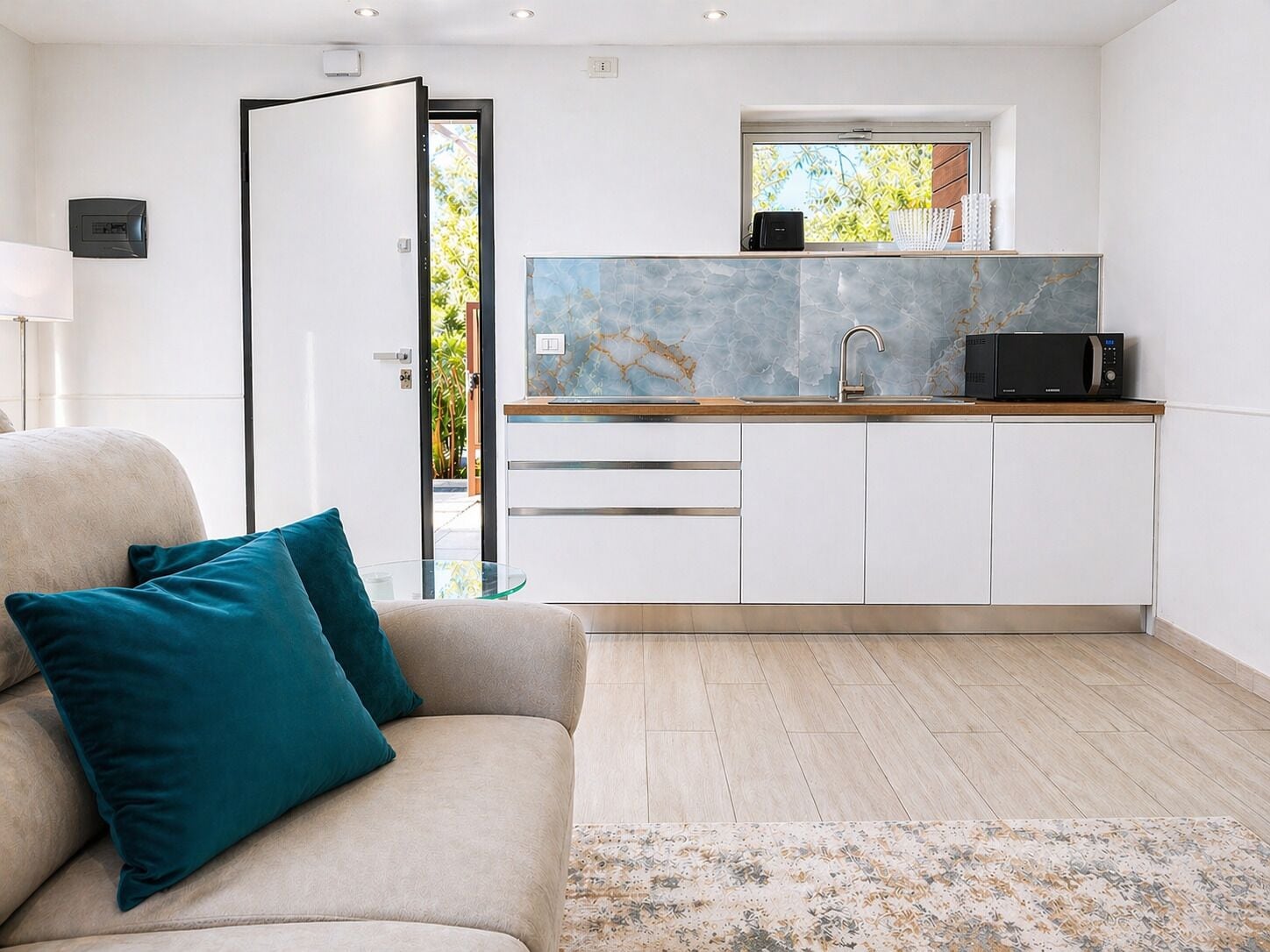 A modern kitchen with a built-in microwave, a sink, and a window with a view of greenery.