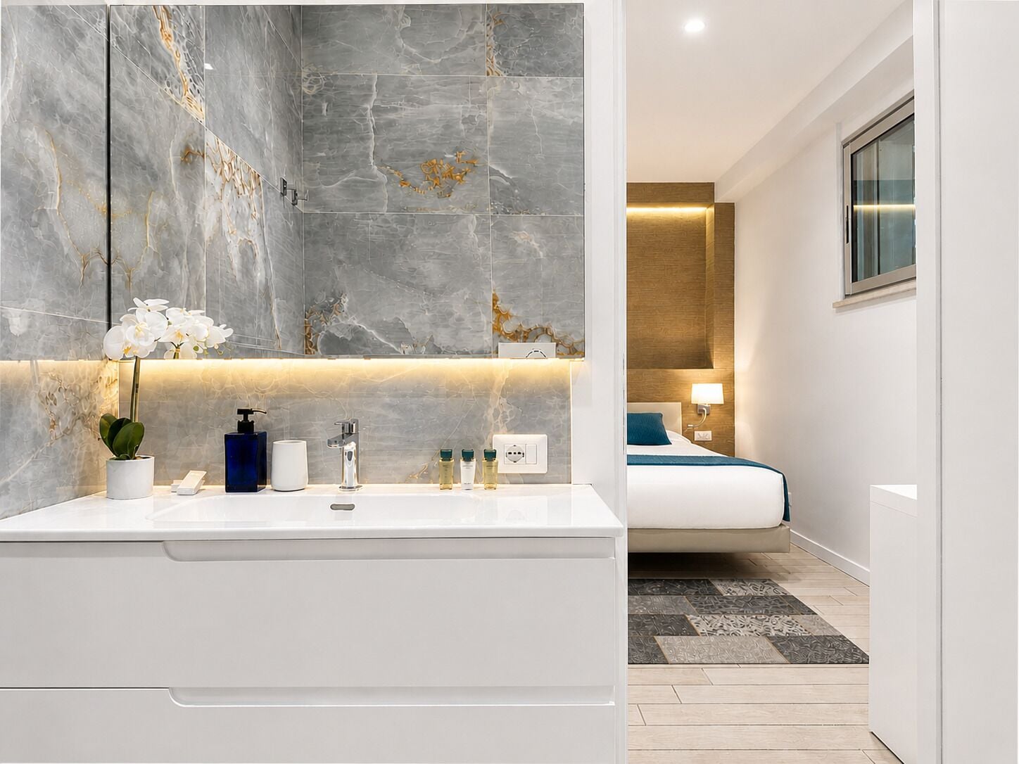 A modern bathroom with a large mirror, a white sink, and a potted orchid.