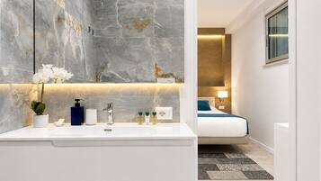 A modern bathroom with a large mirror, a white sink, and a potted orchid.