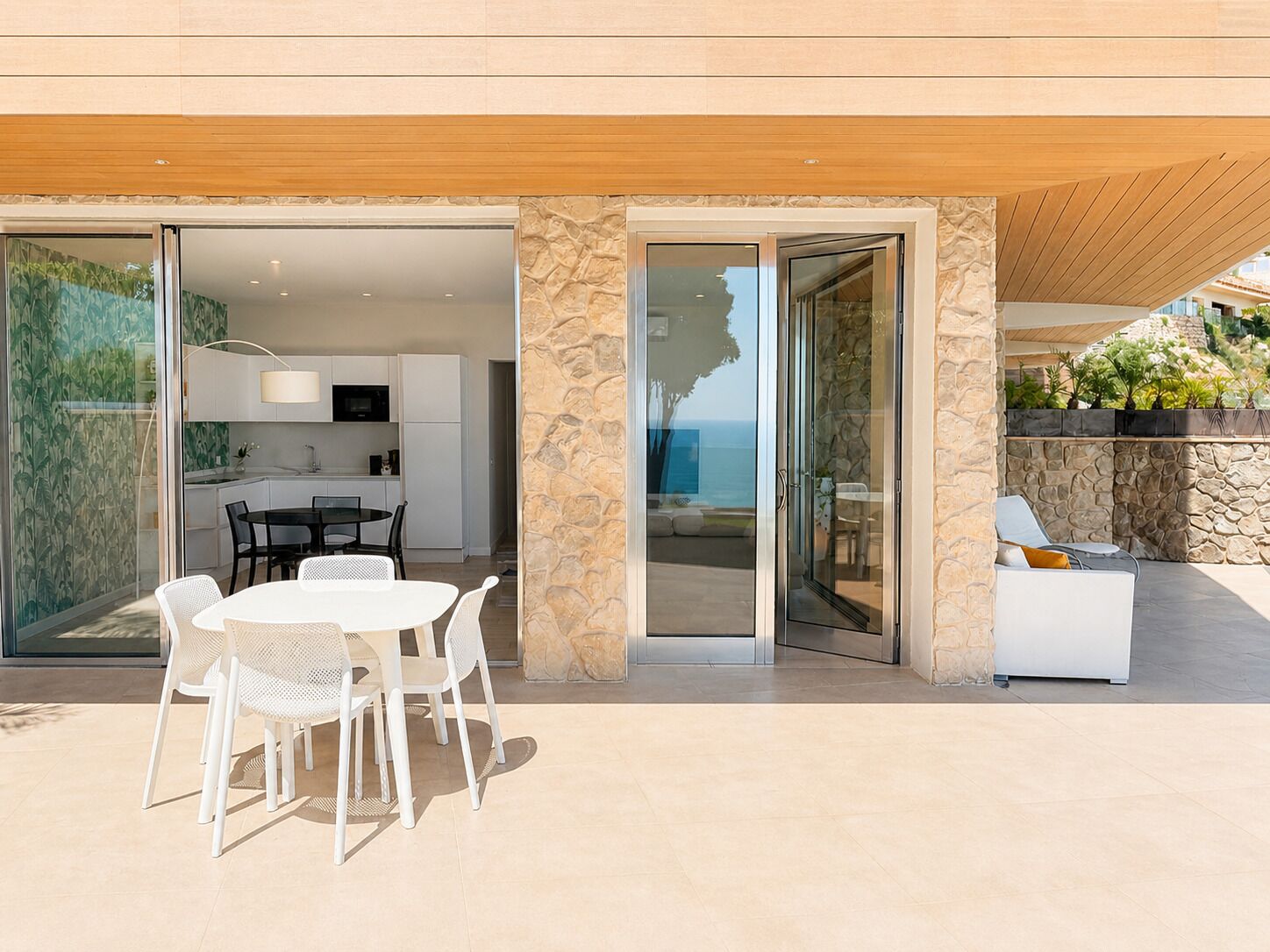 Une maison moderne dotée d’un coin repas, d’une cuisine et d’une terrasse offrant une vue sur la mer.