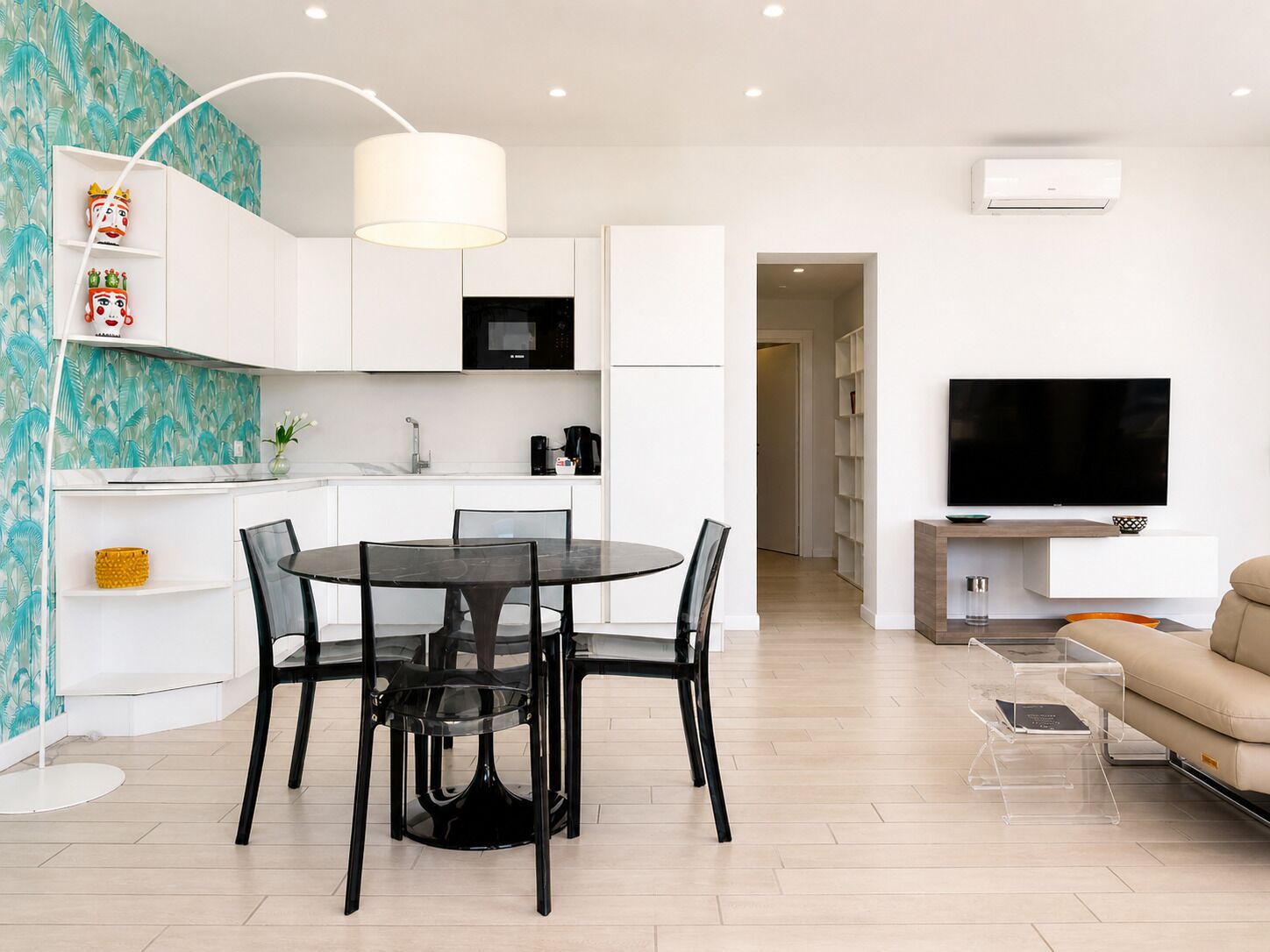 A modern living room with a dining area, a kitchen, a TV, and a sofa.