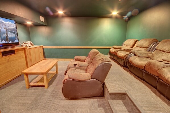 A home theater room with a large screen, leather recliner sofas, and a wooden coffee table. - Springs 8902 (Keystone)