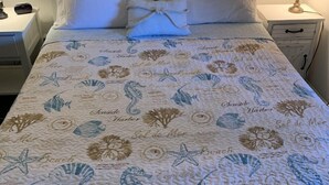 A bed with a quilt featuring sea-themed designs, flanked by bedside tables with lamps. - Spacious.. & Ready for Summer Fun!!Sat-Sat summer booking only (Myrtle Beach)