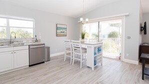 A modern kitchen with white cabinetry, a dishwasher, and a dining area with white chairs and a table. - Lovely Pet Friendly Condo a Block from Siesta Key Village, Two Pools & Tiki Bar (Sarasota)