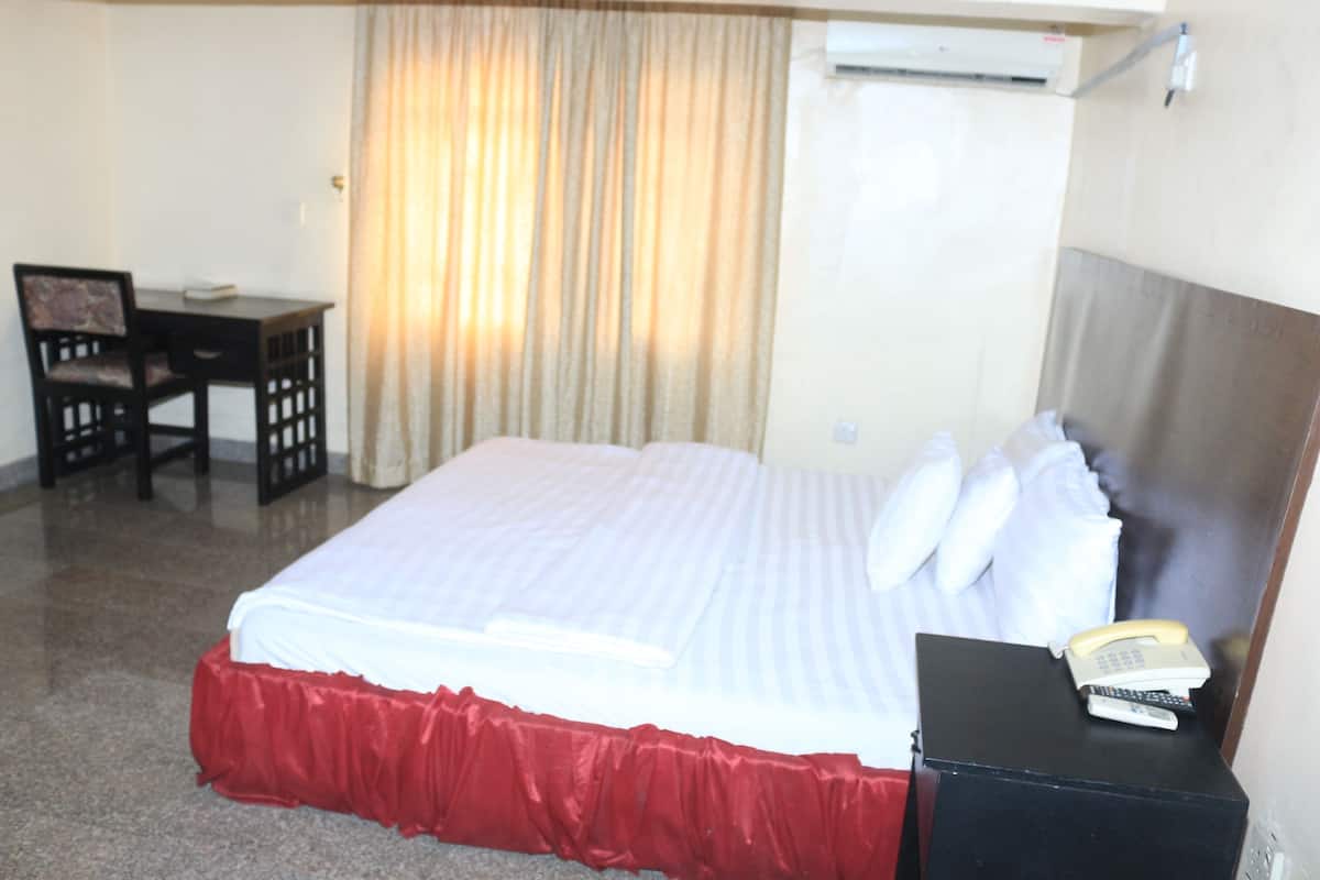 Une chambre d’hôtel équipée d’un lit, d’un bureau, d’une chaise et d’un téléphone.