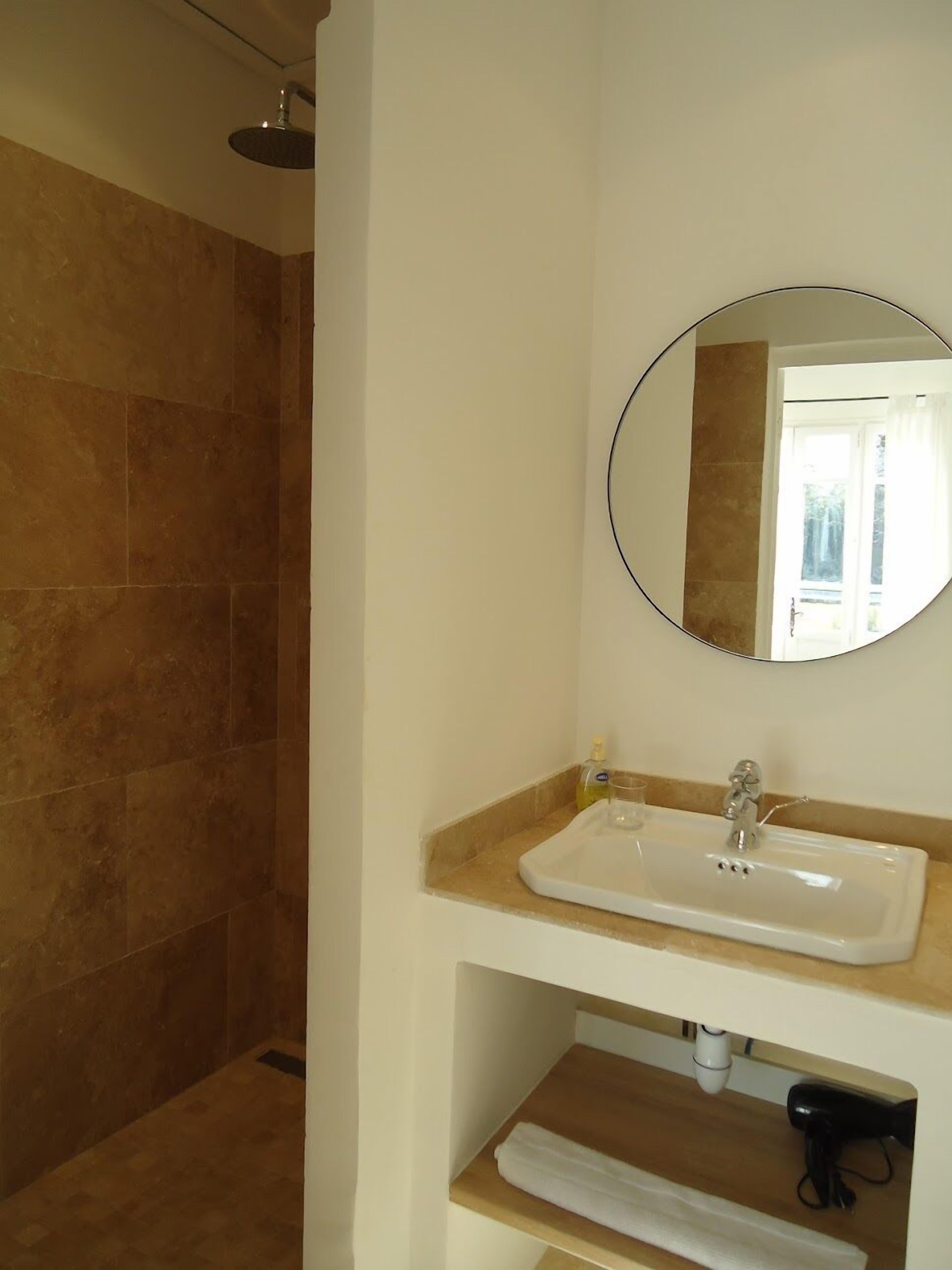 Une salle de bain équipée d’une douche, d’un lavabo, d’un miroir et d’un porte-serviettes.