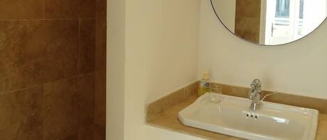 Une salle de bain équipée d’une douche, d’un lavabo, d’un miroir et d’un porte-serviettes.