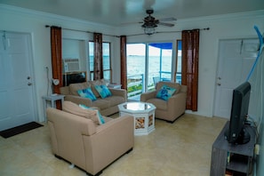Relax in this inviting living room with a beige sofa, flat-screen TV, and ocean views.