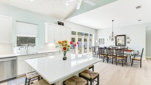 Una cucina moderna con una grande isola, mobili bianchi e vista all'esterno.
