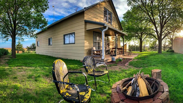 A two-story house with a porch, a fire pit, and outdoor seating. - Rustic Farmhouse Retreat (McCook)