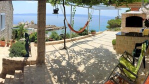 Un bâtiment en pierre doté d’une terrasse avec vue sur la mer, d’un hamac et d’un espace barbecue.