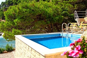 A rectangular swimming pool with clear blue water, surrounded by a stone wall. - Perfect Beachfront Holiday In a Secluded Traditional Stone House With Pool (Mimice)
