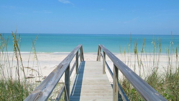 A wooden boardwalk leading to a beach with clear blue water and a clear sky. - Comforts of Home in Condo w/ Pool a Block from Siesta Key Village, Pet Friendly (Sarasota)