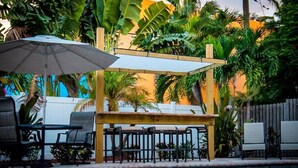 A pool area with a wooden pergola, lounge chairs, and an umbrella. - Comforts of Home in Condo w/ Pool a Block from Siesta Key Village, Pet Friendly (Sarasota)