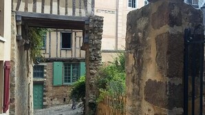 Un estrecho callejón adoquinado con un muro de piedra a un lado y un edificio de estructura con entramado de madera al otro.