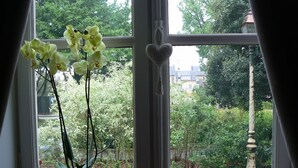 Una ventana con un adorno en forma de corazón y una orquídea en maceta.
