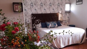 Un dormitorio con cama, mesita de noche, teléfono en la pared y ventana con persianas.