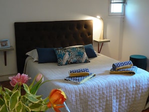 Un lit bien fait, avec une tête de lit matelassée, deux oreillers et des serviettes pliées.
