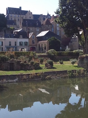Une ville historique, avec ses bâtiments en pierre, un canal et un parc où se trouvent des ruines en pierre.