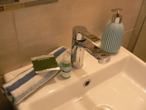 Un lavabo de salle de bain avec une serviette, un flacon de savon liquide et un distributeur de savon.