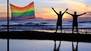 Twee silhouetten voor een zonsondergang met een regenboogvlag.