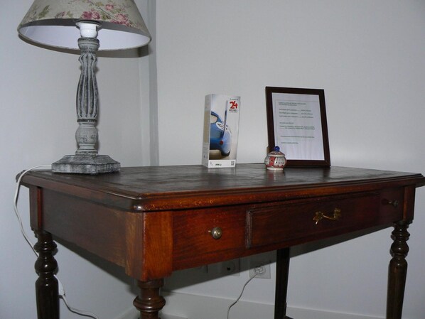 Un bureau en bois avec une lampe, un certificat encadré et une boîte décorée d’une image de voiture.