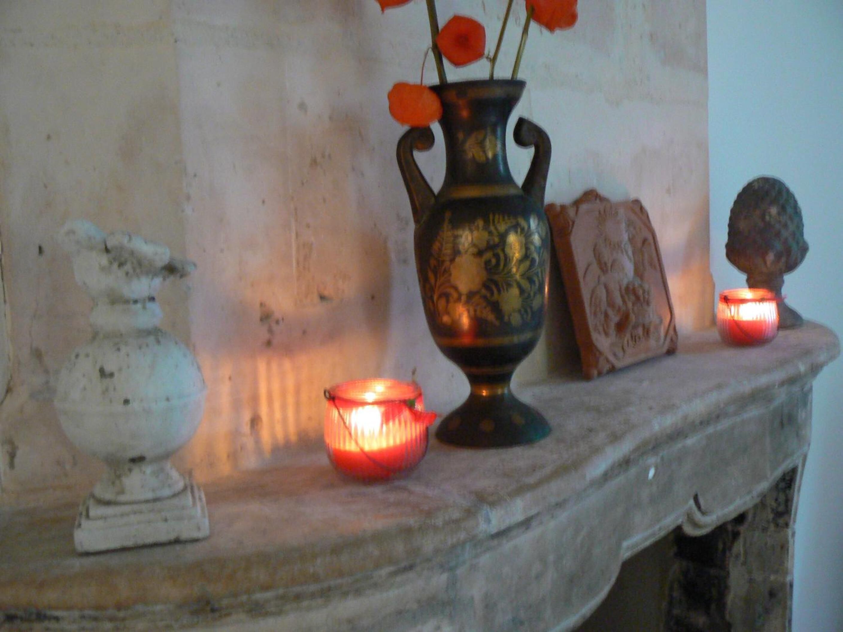 Une étagère en marbre ornée d’un vase décoratif, d’une petite bougie et d’une sculpture.