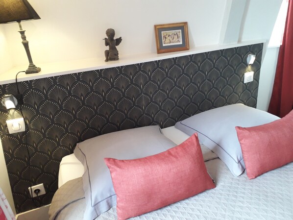 A bedroom with a patterned headboard, two pillows, a bedside lamp, and a framed picture on the wall. - Appartement Relais Saint Pavin (Le Mans)