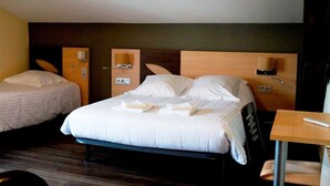 A hotel room with two single beds, a wooden headboard, bedside tables with lamps, and a small desk with a chair. - Hôtel Bellevue (Hendaye)