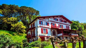 A two-story building with a red and white facade, multiple balconies, and a stone base. - Hôtel Bellevue (Hendaye)