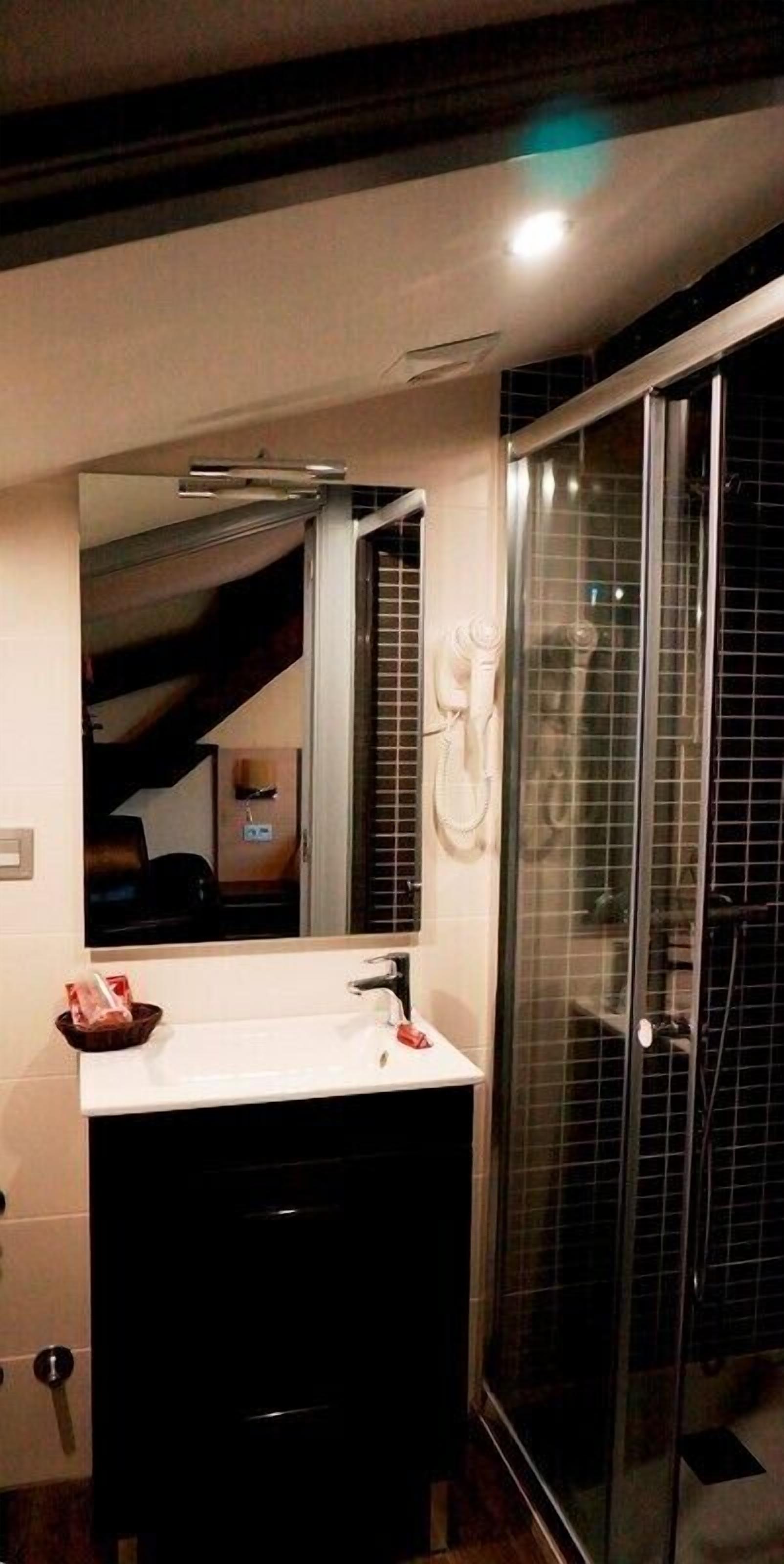 Ein modernes Badezimmer mit einem weißen Waschbecken, einem Spiegel und einer Duschkabine aus Glas.