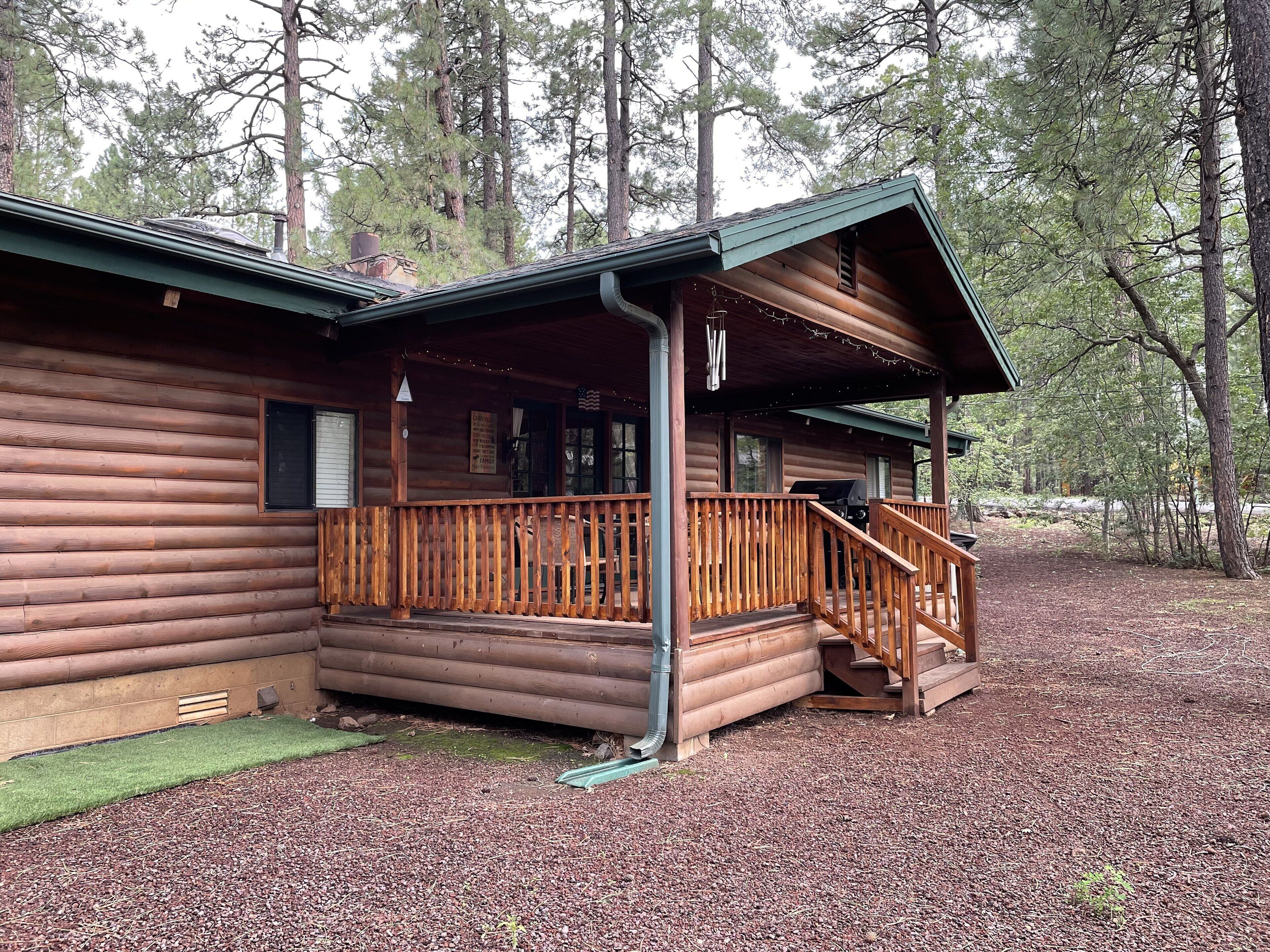 A log cabin with a wooden deck and a covered porch.