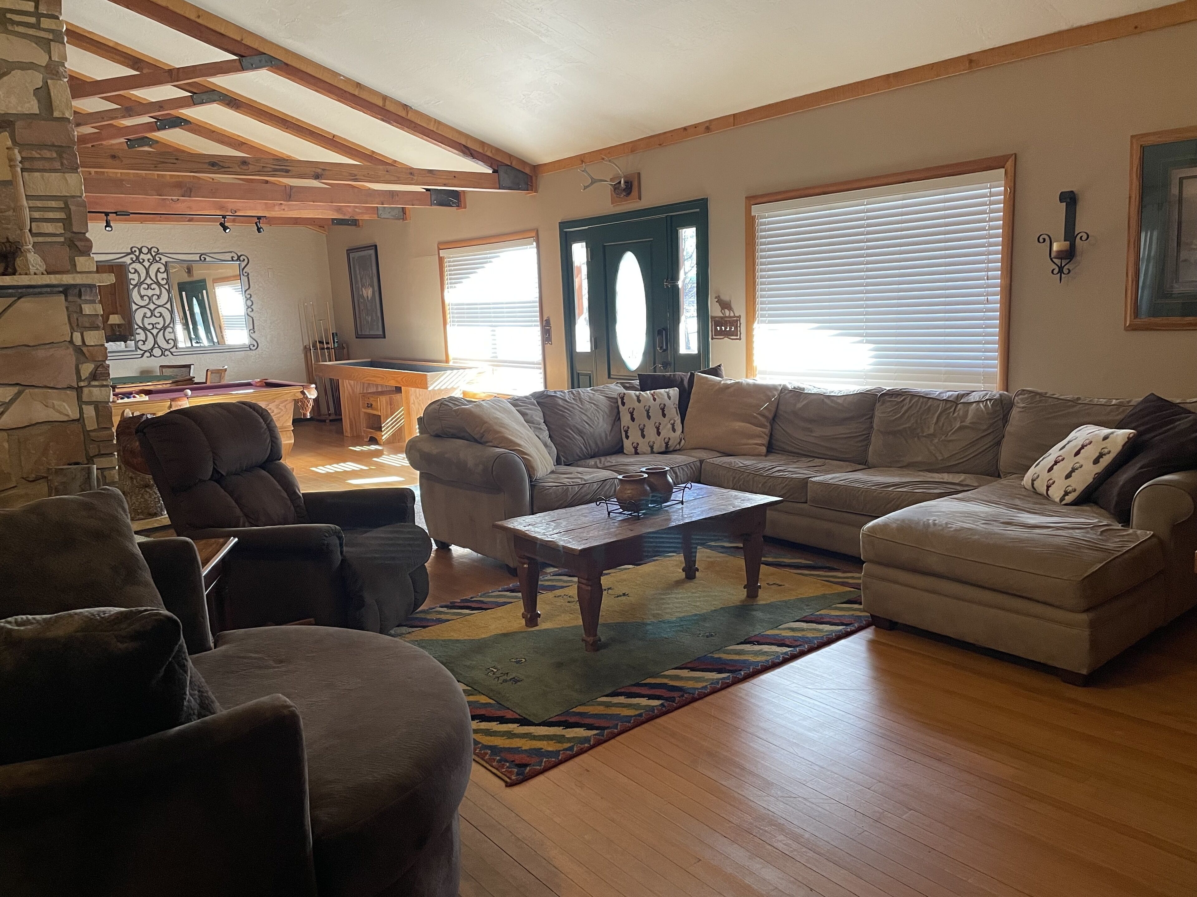 A spacious living room with a large sofa, a coffee table, and a stone fireplace.