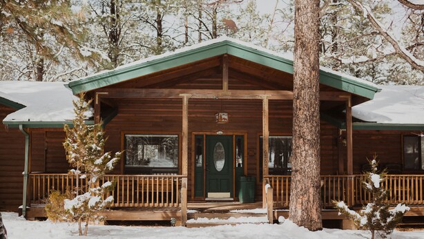 A wooden cabin with a green door, a porch, and a snow-covered landscape. - Perfect for family gatherings, escapes, retreats or seasonal vacations (Pinetop)