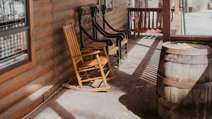 A log cabin with a wooden porch, a rocking chair, a wooden table, and a barrel. - Perfect for family gatherings, escapes, retreats or seasonal vacations (Pinetop)
