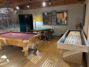 Une table de billard, une table de baby-foot et un coin repas avec des chaises et une table.